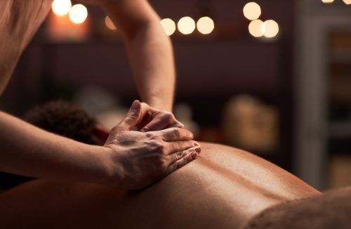 Massage therapist applying light touches when massaging back of client